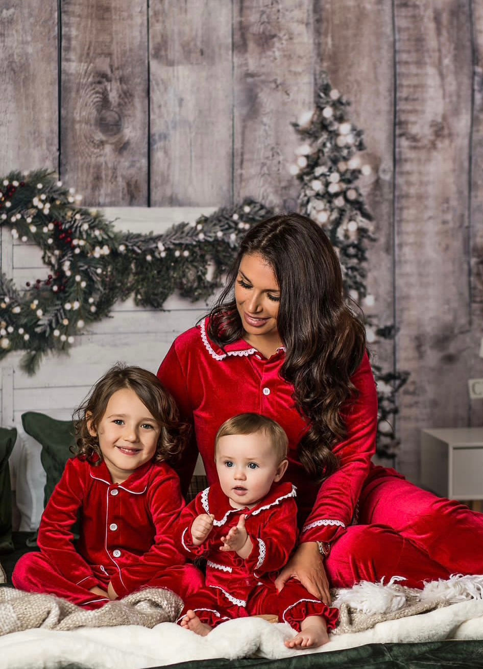 Adult and two children wearing coordinating red velvet Christmas pyjamas