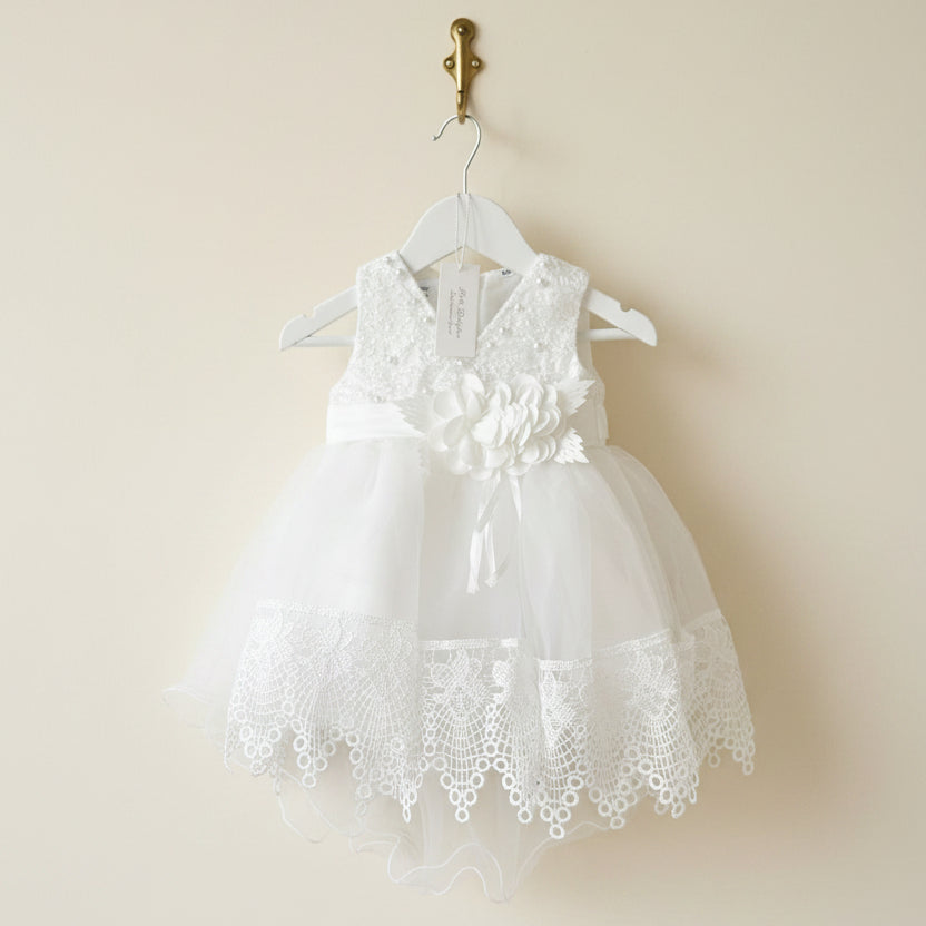 Close up detail of the Amelie Ivory Lace Special Occasion Dress hanging on a white wooden hanger by Little Babybox.