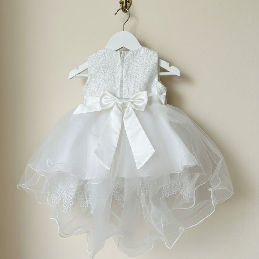 Back view detail of the Amelie Ivory Lace Special Occasion Dress showcasing the large satin bow closure on a white wooden hanger by Little Babybox.