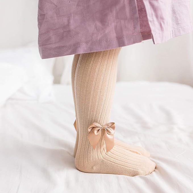Beige knee-high socks with a bow on a white surface