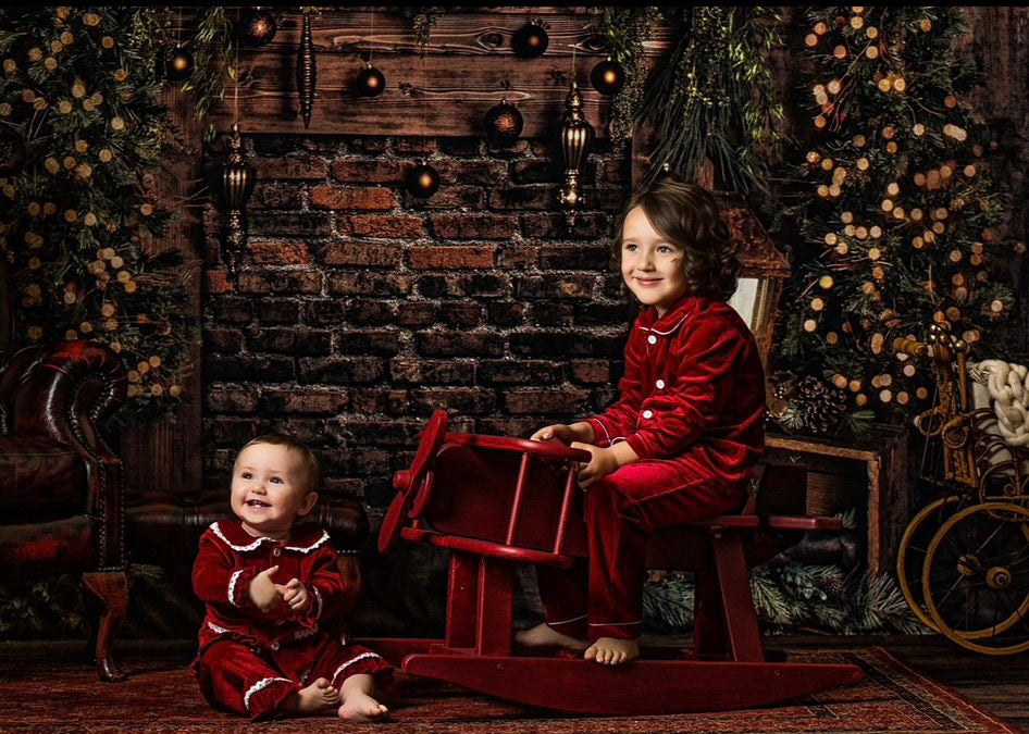 Children in coordinating red velvet Christmas nightwear with a rocking horse