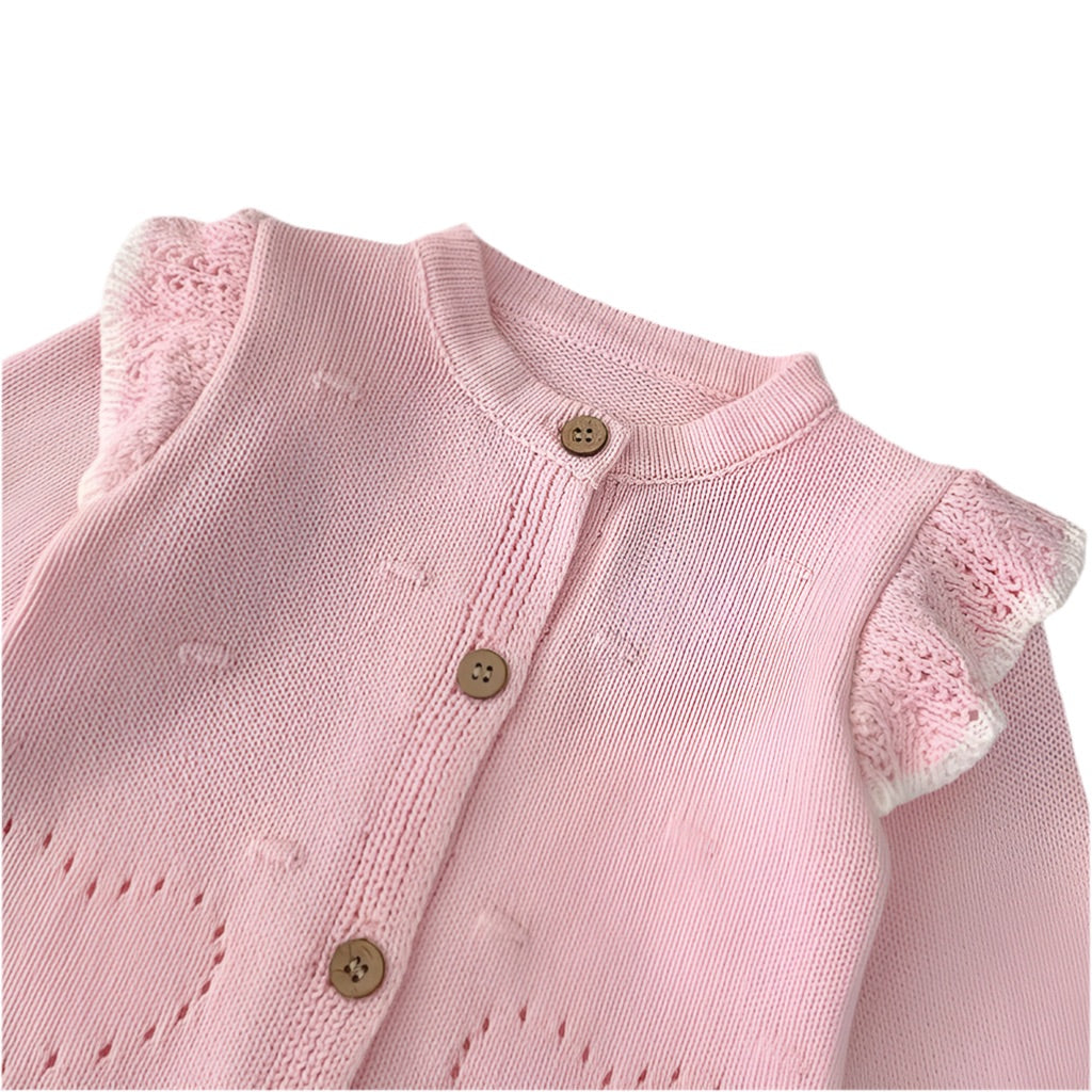 Close-up of Paloma pale pink knit cardigan showing wooden button fastening, openwork heart detail and ruffle shoulder - Little Babybox