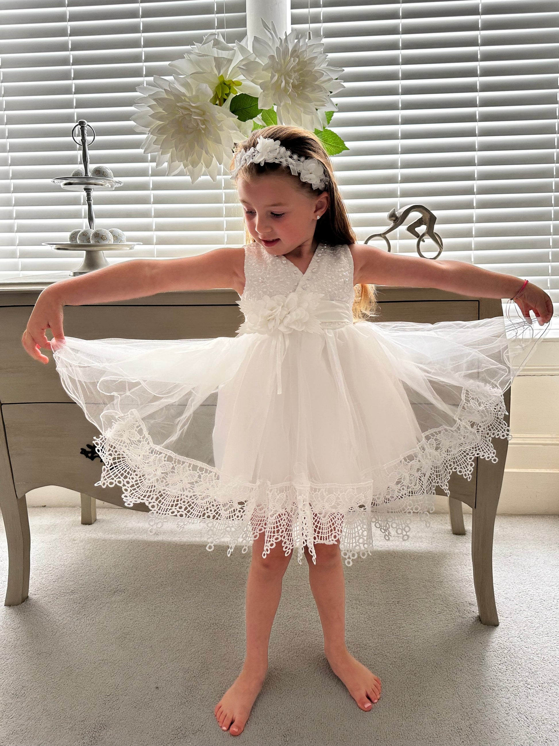 The intricate scalloped lace border on the hem of the handmade ivory white flower girl gown by Little Babybox