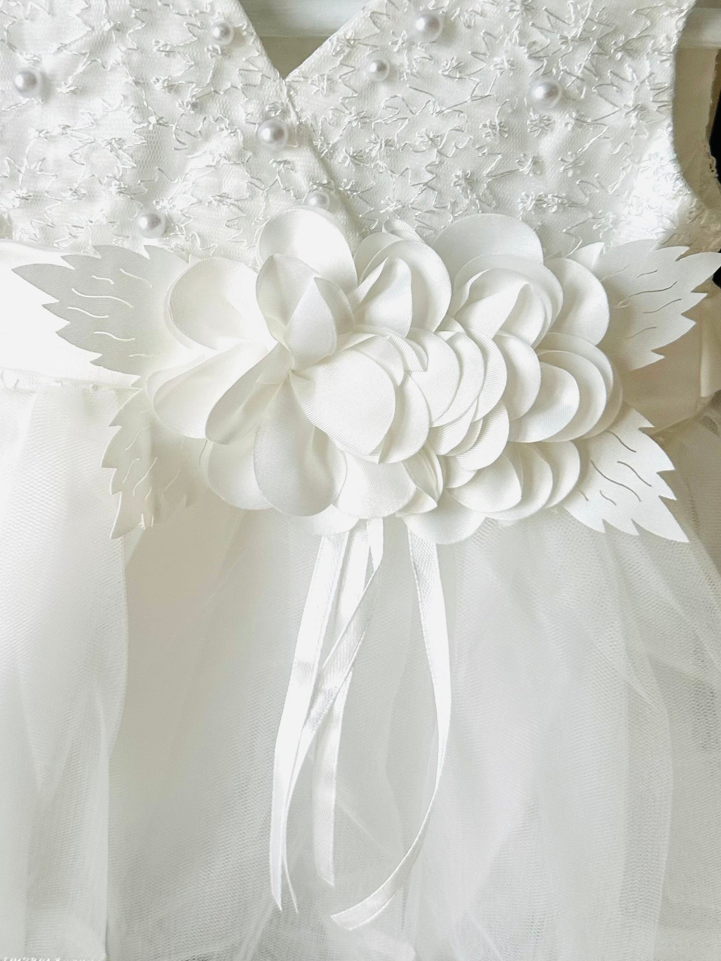Detailed view of the handmade fabric flower centrepiece corsage on the ivory white special occasion baby dress by Little Babybox