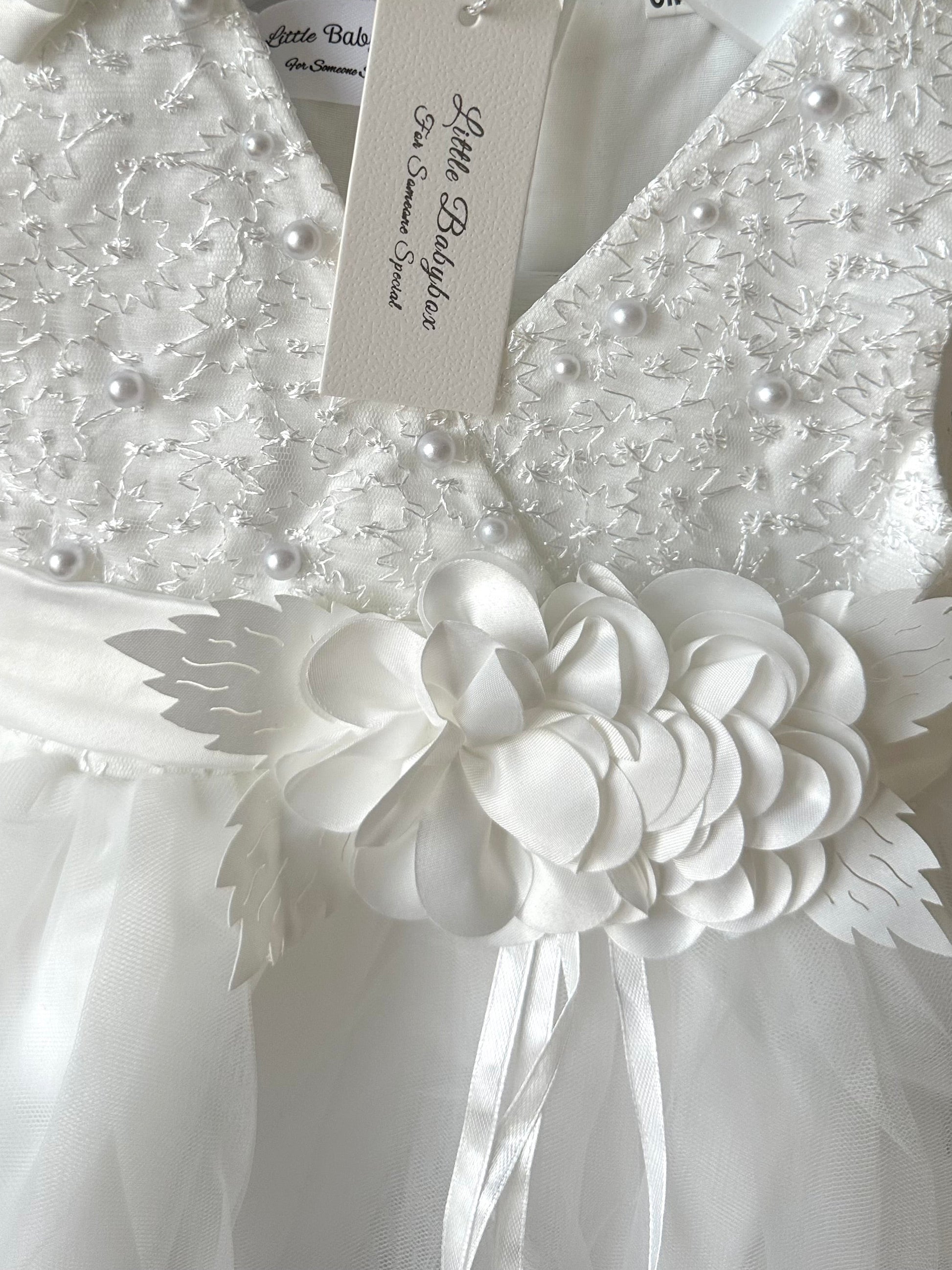 Detail view of the handmade ivory white lace christening dress showing the handmade fabric flower centrepiece and embellished V-neck bodice by Little Babybox
