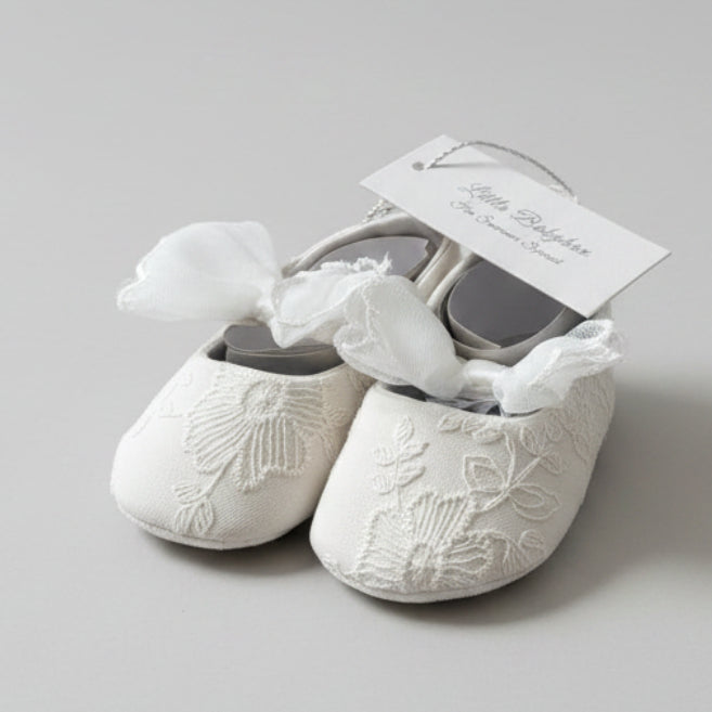 Front view of the Aurelia white fabric baby shoes highlighting intricate floral embroidery on the toes and prominent lace tulle bows