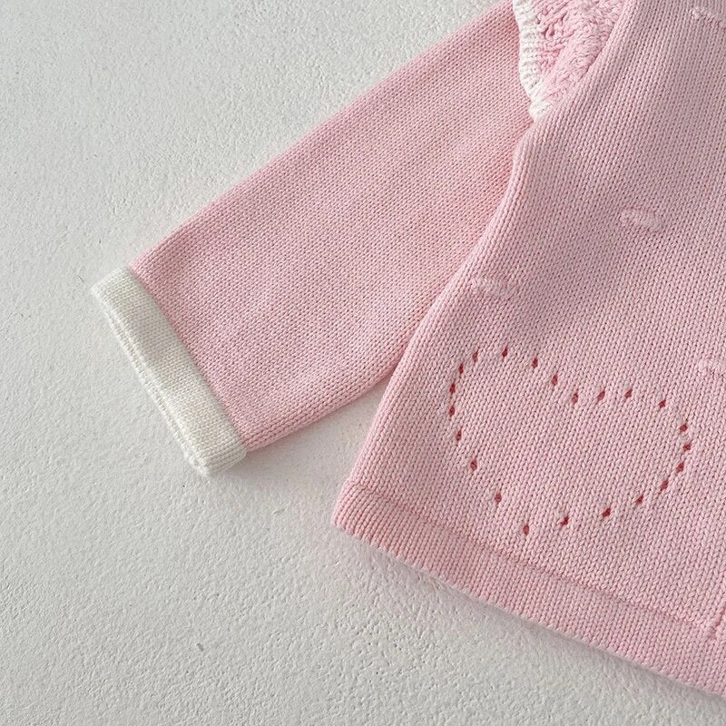 Close-up of Paloma pale pink knit cardigan sleeve showing white trim cuff and openwork heart stitch detail - Little Babybox